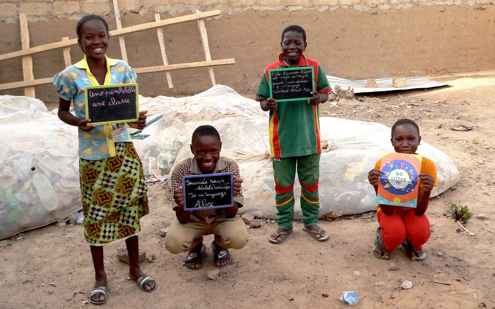 Four children holding blackboard signs, smiling at the camera