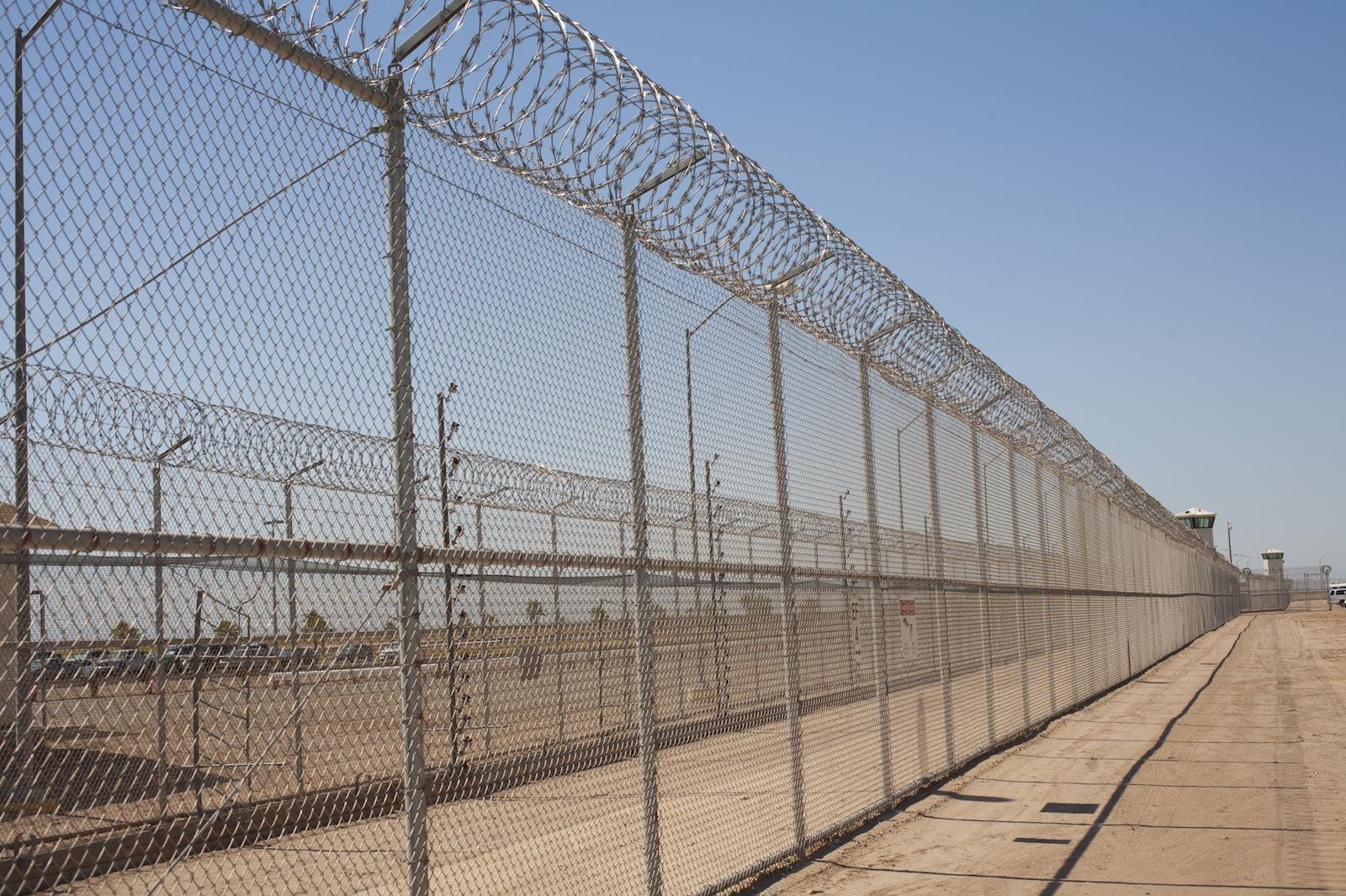 Barbed wire fence and watch towers in desert. 