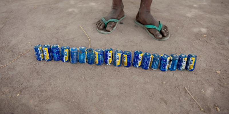 Line of cans in front of a pair of feet
