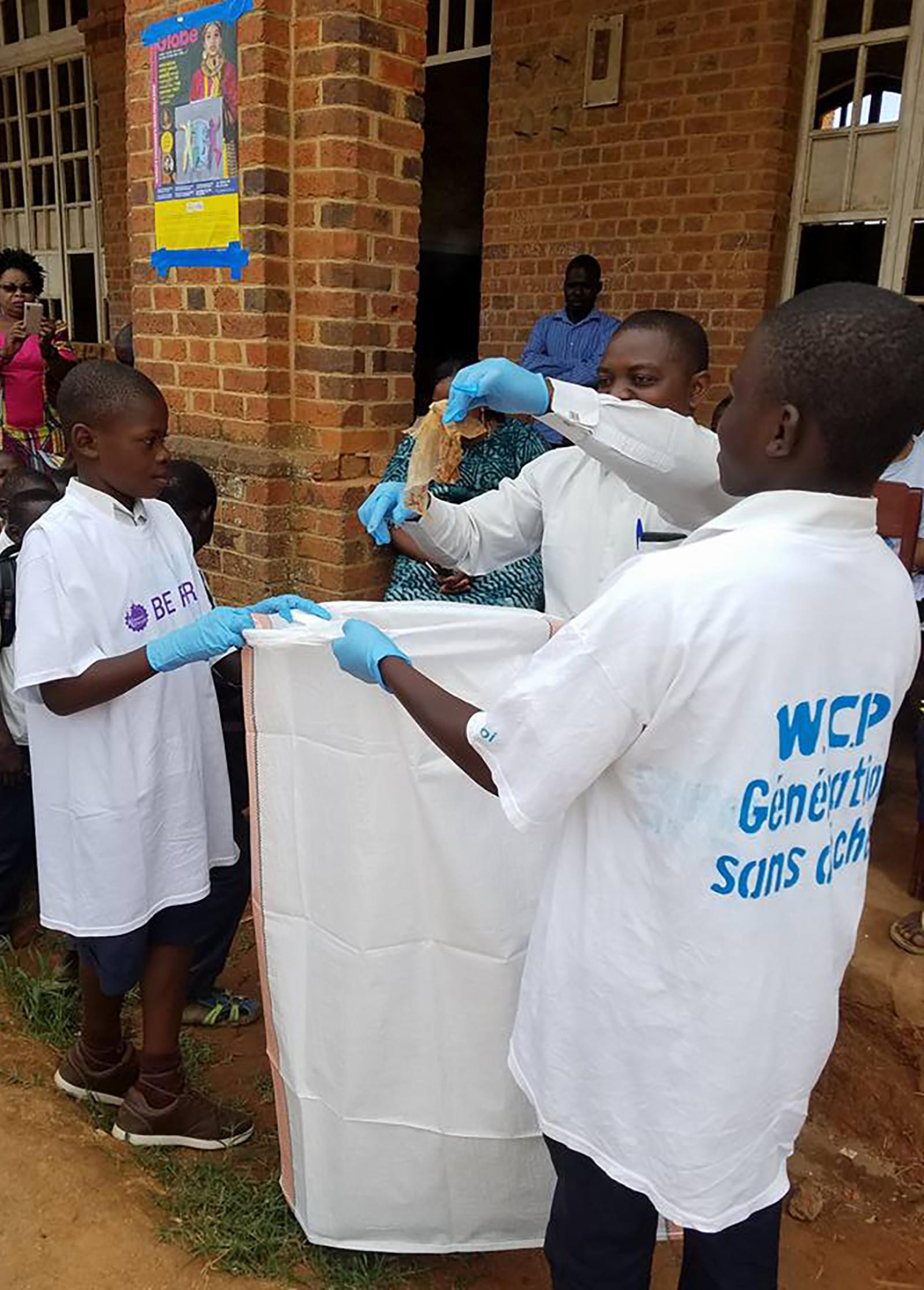 Children in white shirts collecting litter