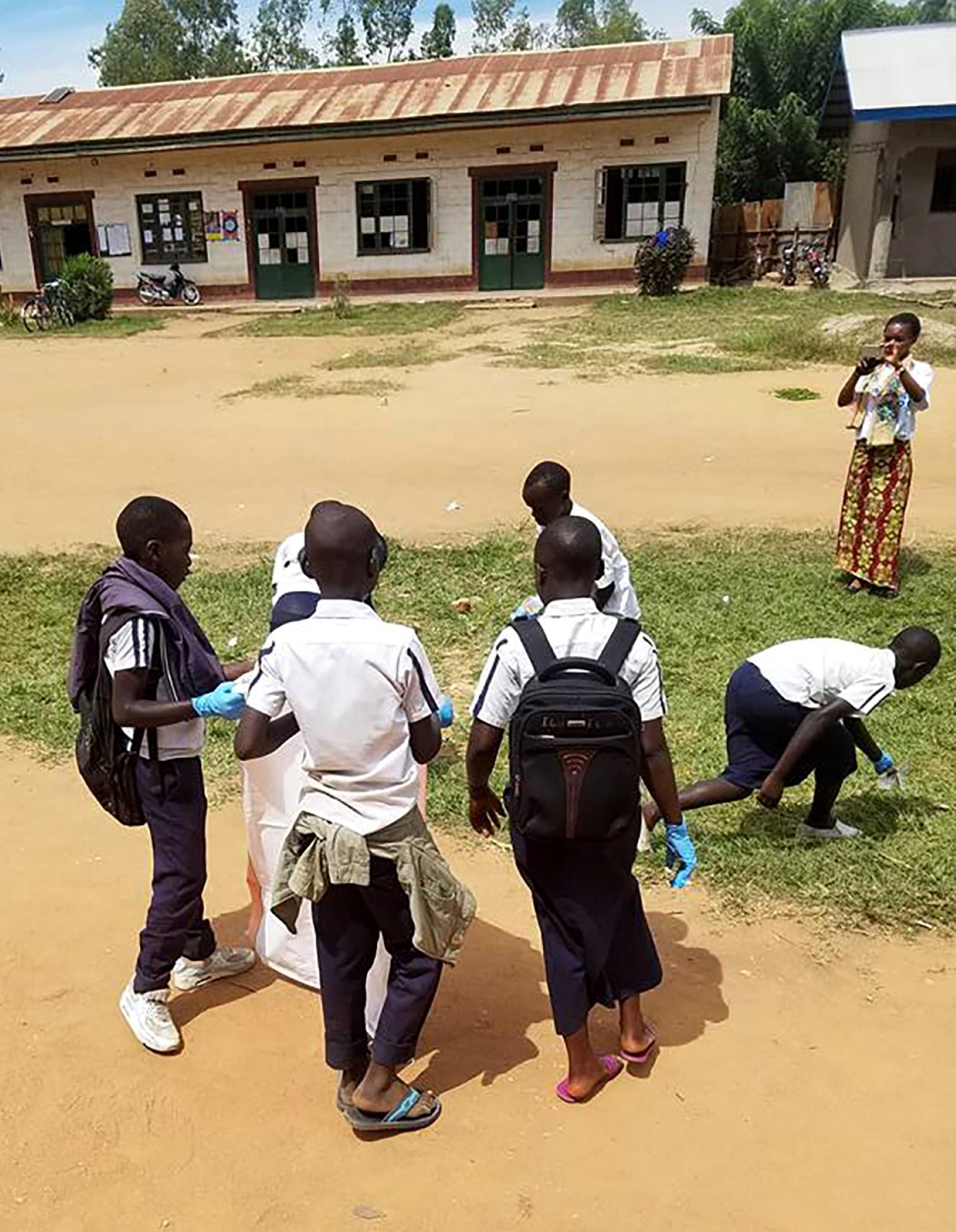 Children getting photographed outside, wearing backpacks and blue plastic gloves
