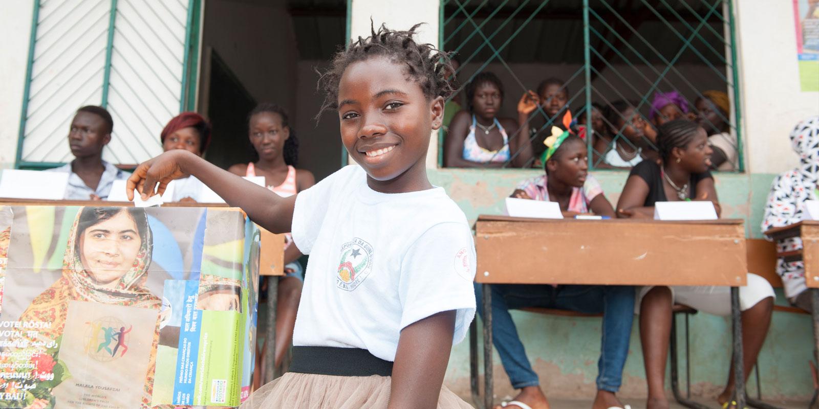 Girl casting vote in ballot box.