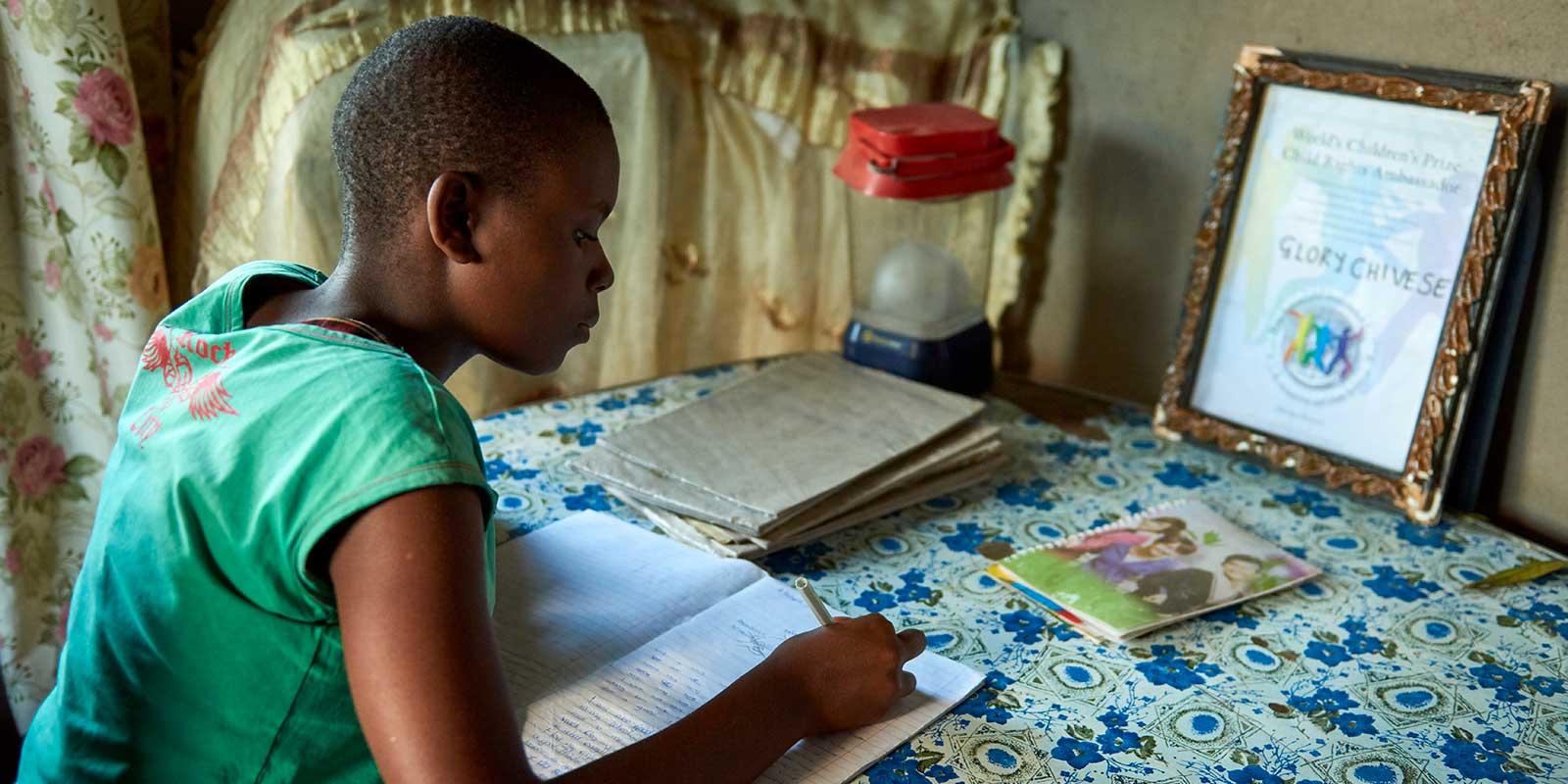 Glory sits at desk, studying, with her diploma
