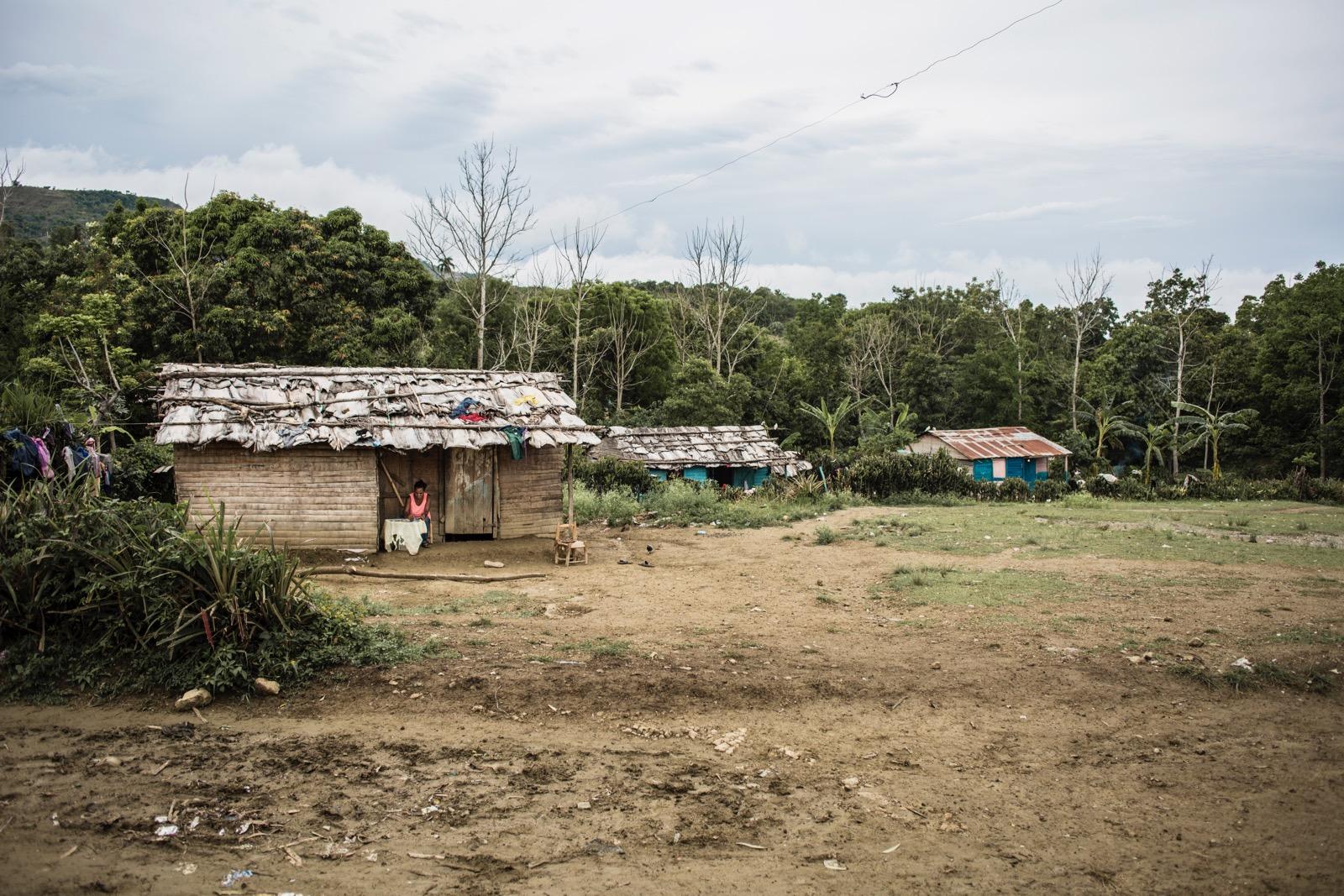 A couple of wooden houses, with a girl sitting in front of one of them.