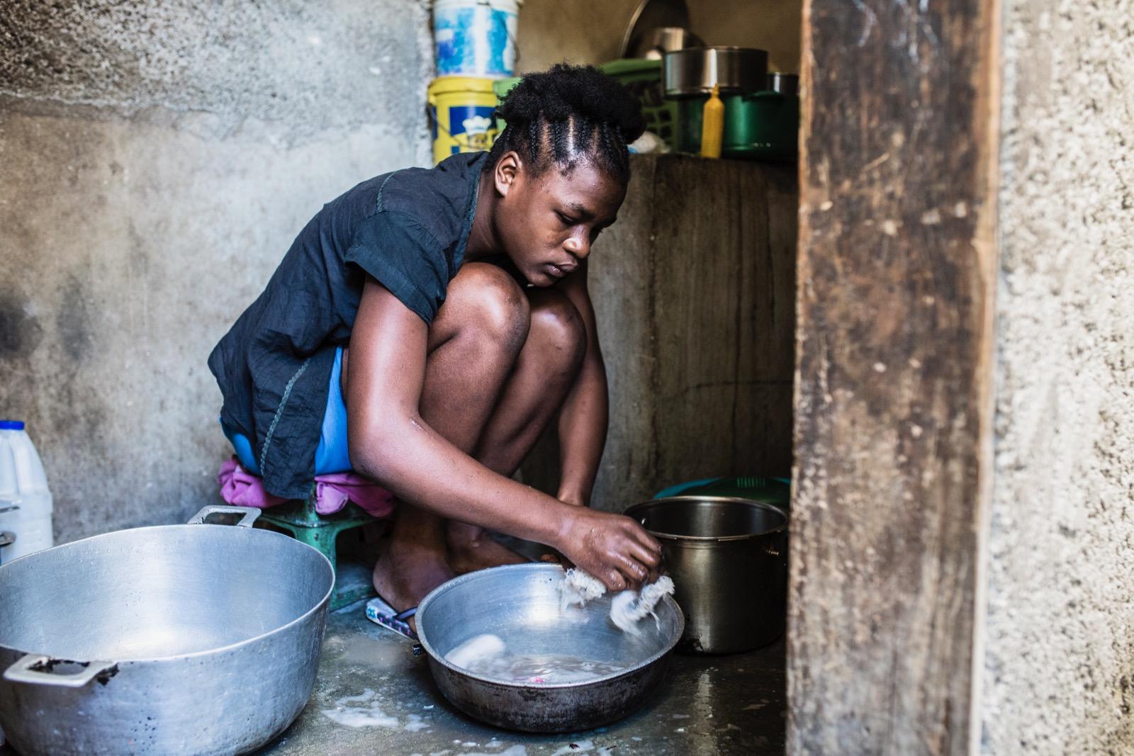 A girl doing the dishes in a tub.