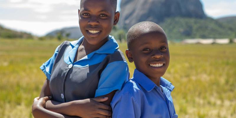 Kim and Hassan, girl and boy, 13, face the camera, wearing their school uniforms.  