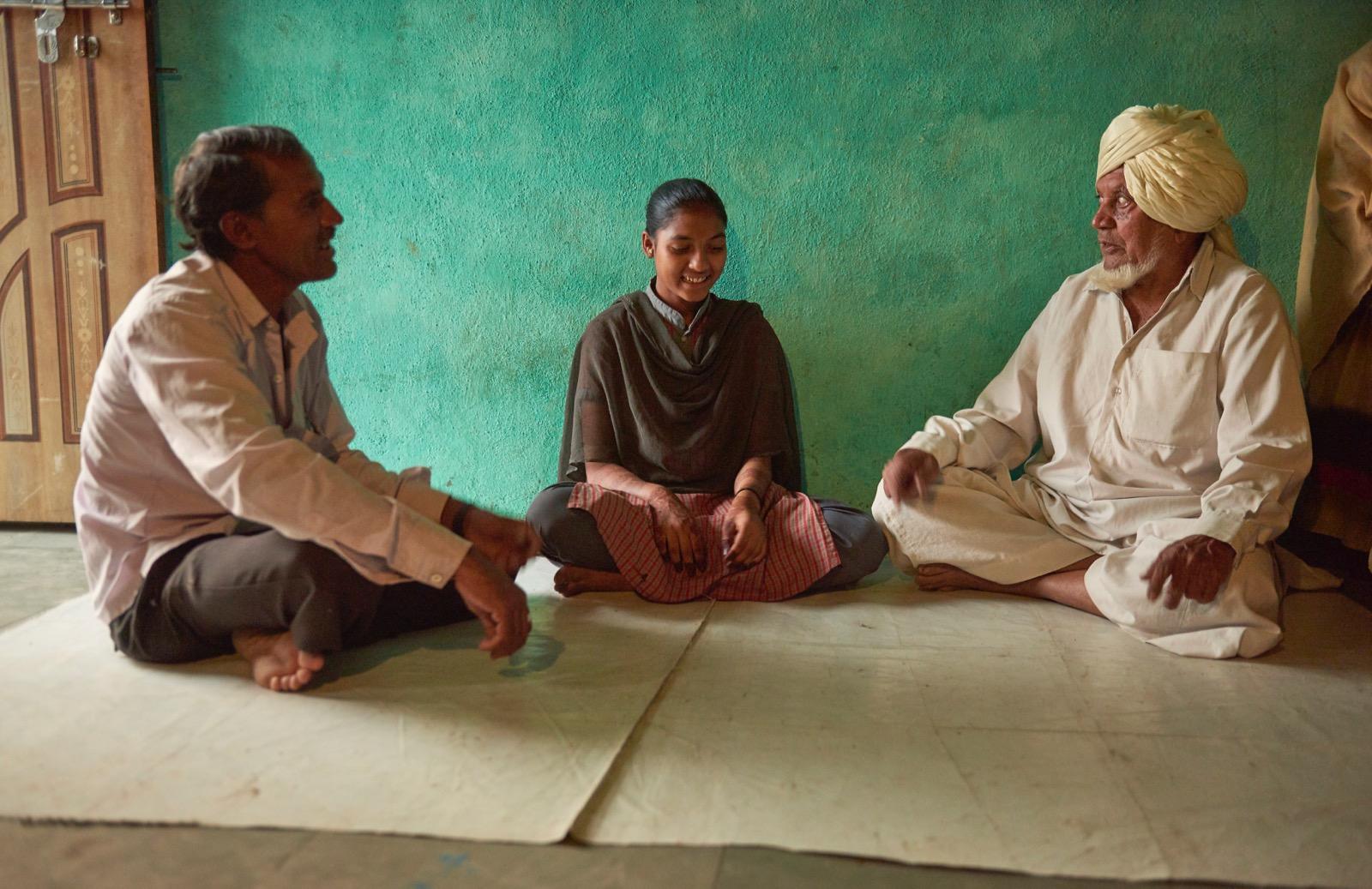a girl and two men sitting down