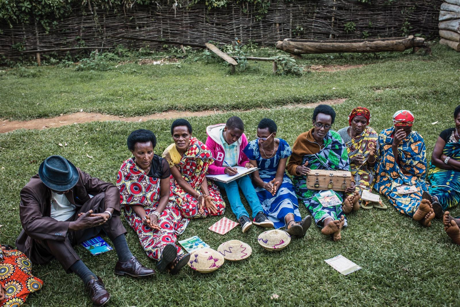 A group of people sitting on a field of grass.